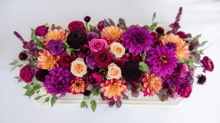 A vibrant bouquet of wildflowers including dahlias, roses, and small blooms in rich purple and warm tones,