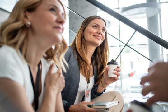 Businesswomen enjoying coffee break on stairs during conference