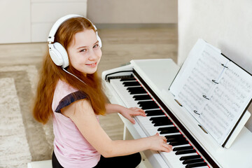 smiling cute girl in headphones playing piano