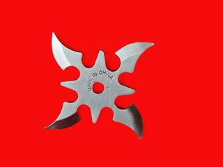 Throwing star shuriken, traditional Japanese ninja bladed weapon on red background. Made in China inscription.