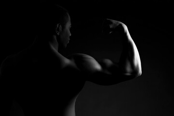 silhouetted bodybuilder flexing muscles against solid monochrome background ensuring ample copy space