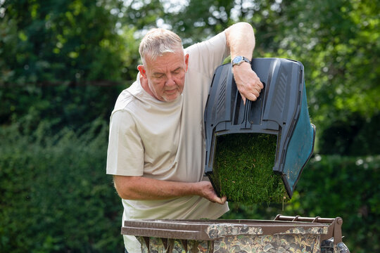 man emptying lawnmower grass box