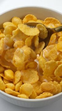 Corn flakes cereal with milk taking with spoon. Cooking traditional family breakfast dry cereal