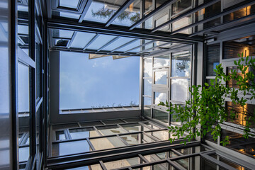 Vue intérieure d’un patio entièrement fermé par des façades vitrées, laissant apparaître le...