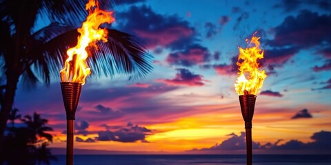 Hawaii luau party Maui fire tiki torches with open flames burning at sunset sky clouds at night