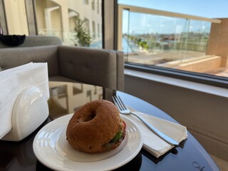 Healthy breakfast with tuna bagel. Bagel with tuna on white plate on cafe table with hotel view from window