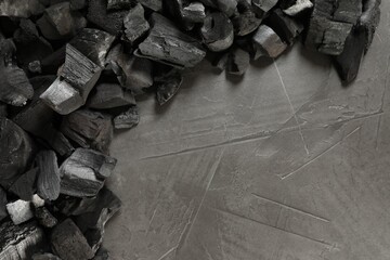 Pieces of black coals on grey table, flat lay. Space for text