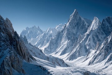 Fototapeta premium Snow-covered mountain range with sharp peaks and deep valleys under a clear blue sky, showcasing glacial landscapes