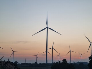Wind Turbines Against Sunset: A captivating scene featuring wind turbines gracefully silhouetted against a stunning sunset, representing renewable energy and environmental sustainability.