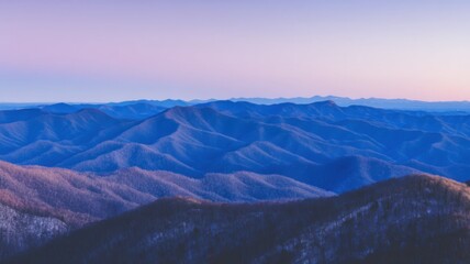 Fototapeta premium Panoramic view of a mountain range at twilight, smooth silhouetted forms with varying shades of blue,