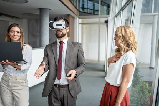 Businessman experiencing virtual reality with vr headset in modern office with colleagues