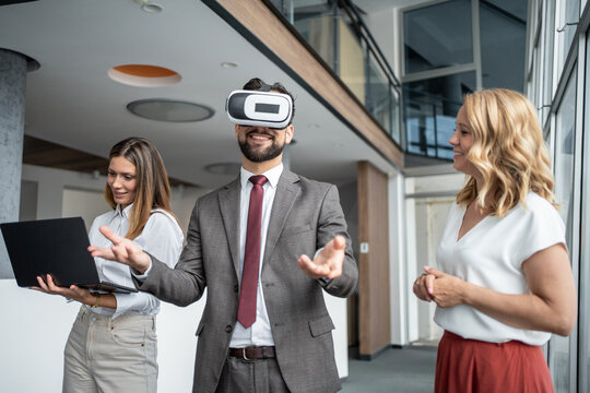 Businessman wearing vr headset interacting with metaverse in office with coworkers