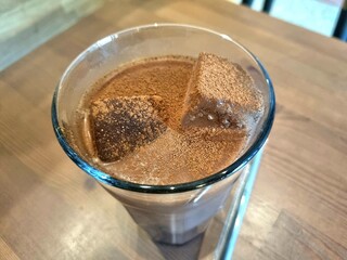 Chocolate Drink Delights: A refreshing chocolate drink with ice cubes sits enticingly in a glass, inviting a moment of pure indulgence. Sprinkled with cocoa powder, it exudes a sense of refreshment.
