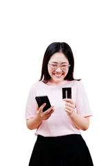 Fototapeta premium A smiling Asian young beautiful woman wearing glasses holds a smartphone in one hand and a credit card in the other, appearing excited and engaged with her purchase or transaction.