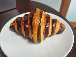 Chocolate Croissant Delight: A freshly baked, flaky chocolate croissant sits elegantly on a clean...
