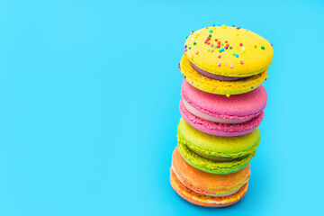A few brightly colored stacked macarons on blue background. Mixed of colorful macaroni or pasta cake. Tasty and colorful french macarons. Culinary, cooking concept, styling food. Add your text.