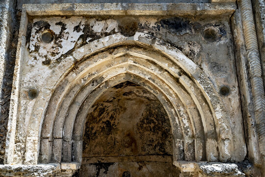 View of the ancient stone archway with weathered textures and dark interior, illuminated by soft light, Gede, Kilifi County, Kenya.