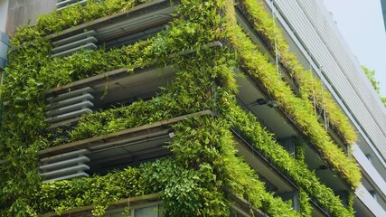 Modern building facade with lush green plants and vertical gardens promoting sustainable urban architecture in Bangkok city, Thailand. Eco friendly urban environment. Eco-friendly architecture