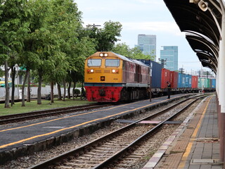 Fototapeta premium Rail Freight: A powerful freight train rolls along the tracks, transporting shipping containers through an urban landscape, showcasing the efficiency and scale of modern transport