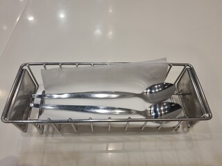 Elegant Flatware Duo: A pair of sleek, polished spoons rest alongside a crisp napkin within a...