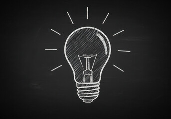 Classic incandescent light bulb drawn with chalk on a dark blackboard surface