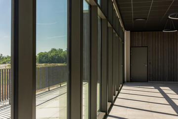 Vue intérieure d’une pièce lumineuse avec une baie vitrée panoramique offrant une vue...