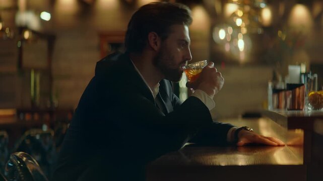 Beautiful Caucasian male sitting in a stylish restaurant, drinking cocktail. Shot with 2x anamorphic lens