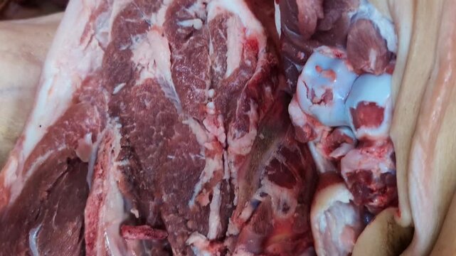 Various cuts of fresh meat displayed in a market showcasing local butchery techniques during daylight hours - Powered by Adobe