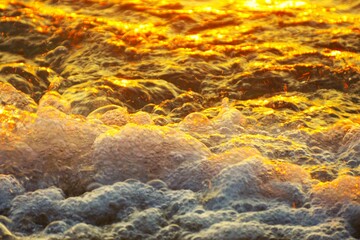Golden wave with foam and bubbles in beautiful sunset