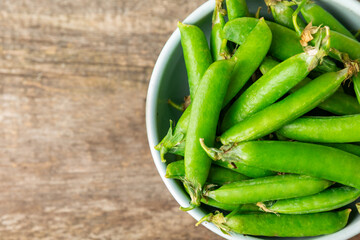 Fresh green pea pods with green peas on a wooden background. Sweet green peas. Green pea beans vegetables. Vegan. healthy vegetable. Copy space
