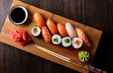 Top view of a gourmet sushi platter served on a wooden board with chopsticks, soy sauce, and wasabi on the side, elegant Japanese restaurant setting, natural lighting
