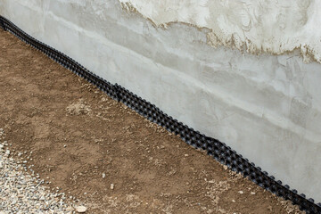 Insulating a house footing with impermeable black foil, side view close up with copy space