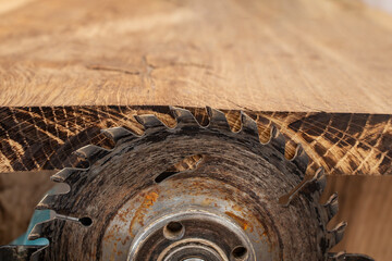 High speed hand grinder with a circular blade cutting hardwood and wood marking the edge of a  oak board