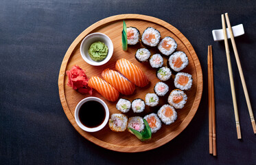Top view of a gourmet sushi platter served on a wooden board with chopsticks, soy sauce, and wasabi on the side, elegant Japanese restaurant setting, natural lighting
