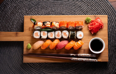 Top view of a gourmet sushi platter served on a wooden board with chopsticks, soy sauce, and wasabi on the side, elegant Japanese restaurant setting, natural lighting
