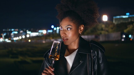 Lady enjoy luxurious alcohol at night street celebration closeup. African woman