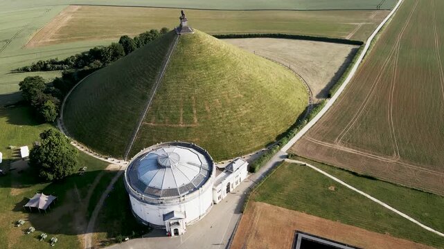 Aerial view of the Lion's Mound, a conical hill with a lion statue at its peak, surrounded by fields, Bruges, Flanders, Belgium.