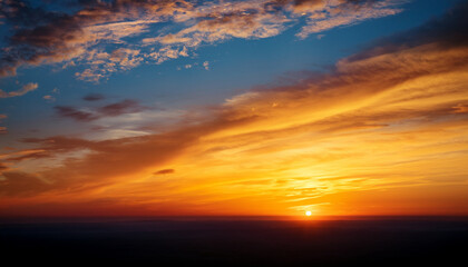 a vibrant orange and yellow sunset sky with wispy clouds at the horizon
