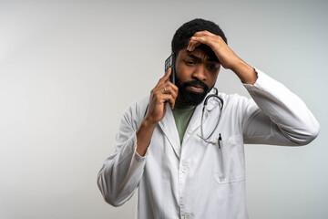 Stressed black male doctor receiving bad news on phone, worried about patient’s poor therapy...