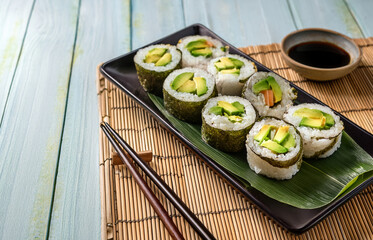 Flatlay of sushi rolls, ginger, wasabi, and soy sauce in small bowls on a clean white background, ideal for menu or packaging mockup
