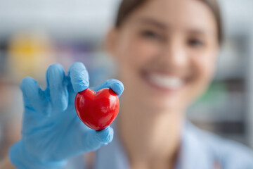 Doctor holds red heart in gloved hand. Shows caring, compassion. Perfect for medical marketing, healthcare designs, or editorial content.