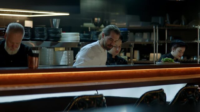 WIDE Caucasian male chef working on modern busy commercial restaurant kitchen. Shot with 2x anamorphic lens