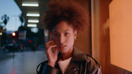 Woman face illuminated urban lights closeup. Portrait curly-haired model posing