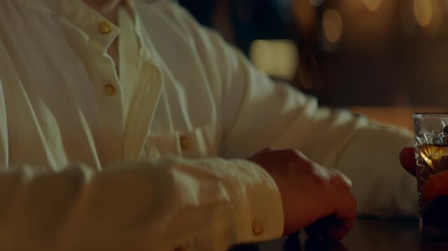 Beautiful Caucasian male sitting in a stylish restaurant, drinking cocktail. Shot with 2x anamorphic lens