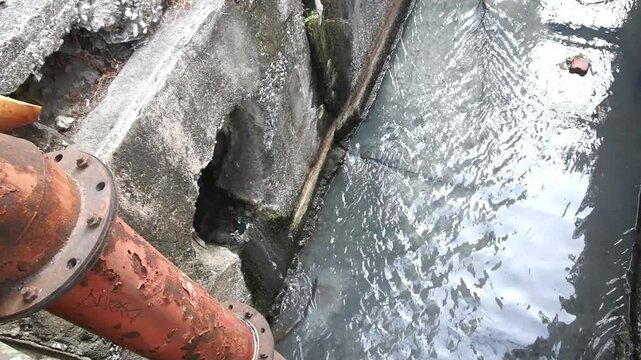 urban drainage system with flowing wastewater and rusty large steel pipe