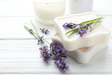Soap bars and lavender flowers on white wooden table, closeup. Space for text
