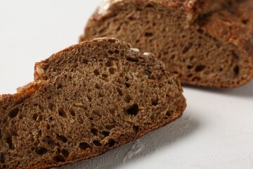 Pieces of fresh rye bread on white textured table, closeup
