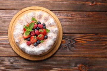 Tasty Bundt cake with powdered sugar and berries on wooden table, top view. Space for text