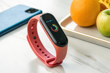 Fitness tracker, Smartwatch on a table beside fruits and a smartphone, showcasing modern technology and lifestyle.
