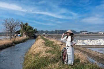 young woman wearing Ao dai costume Vietnam traditional with bicycle.